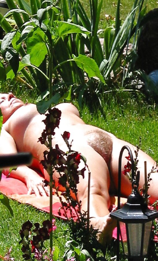 Femme nue en train de bronzer accostée dans le jardin