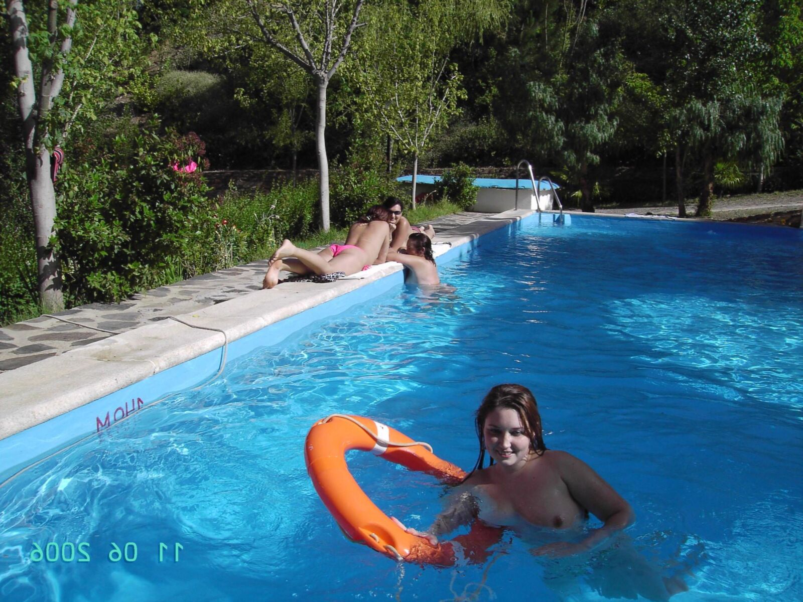 Chica en topless en la piscina del camping