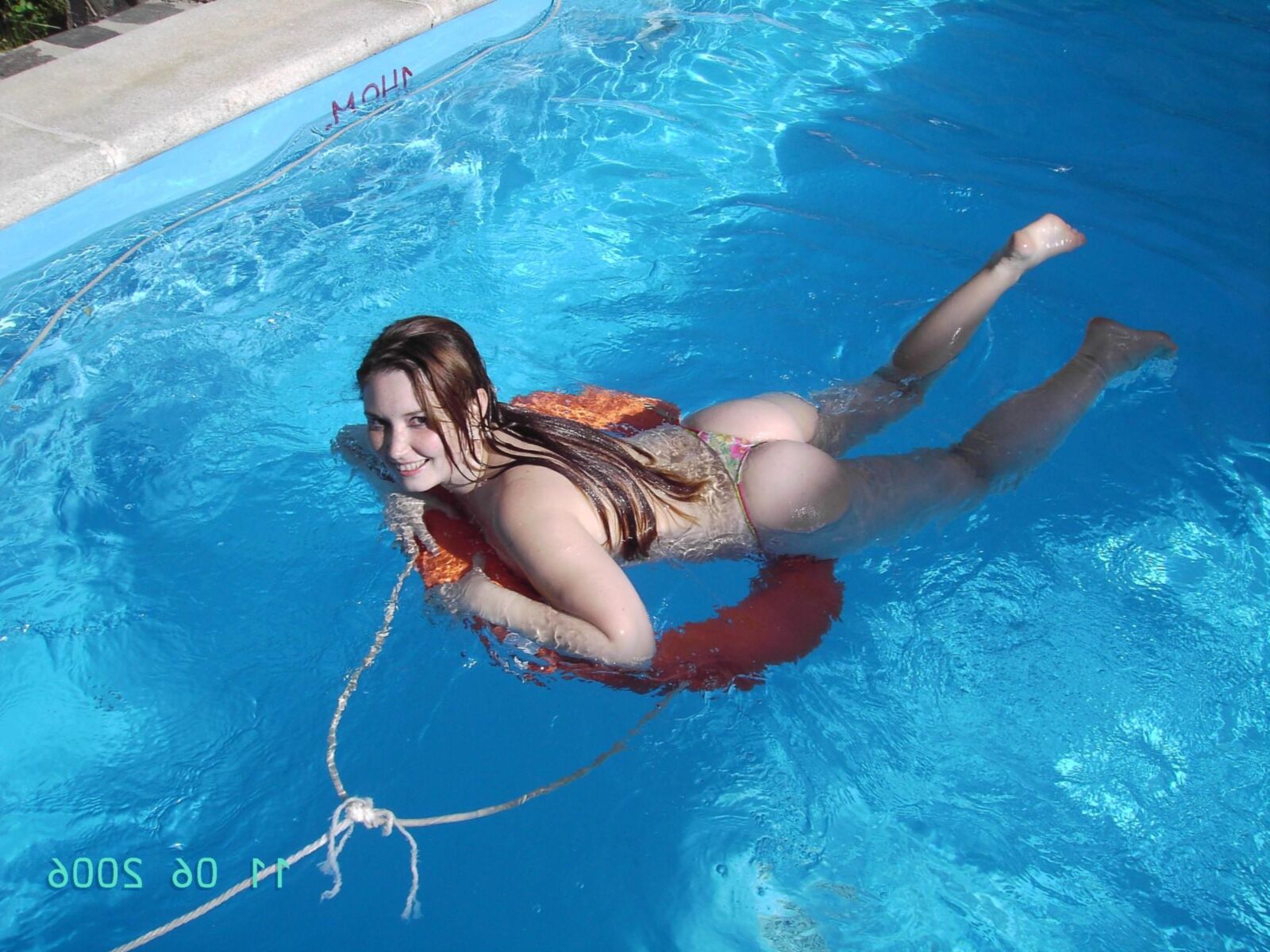 Chica en topless en la piscina del camping