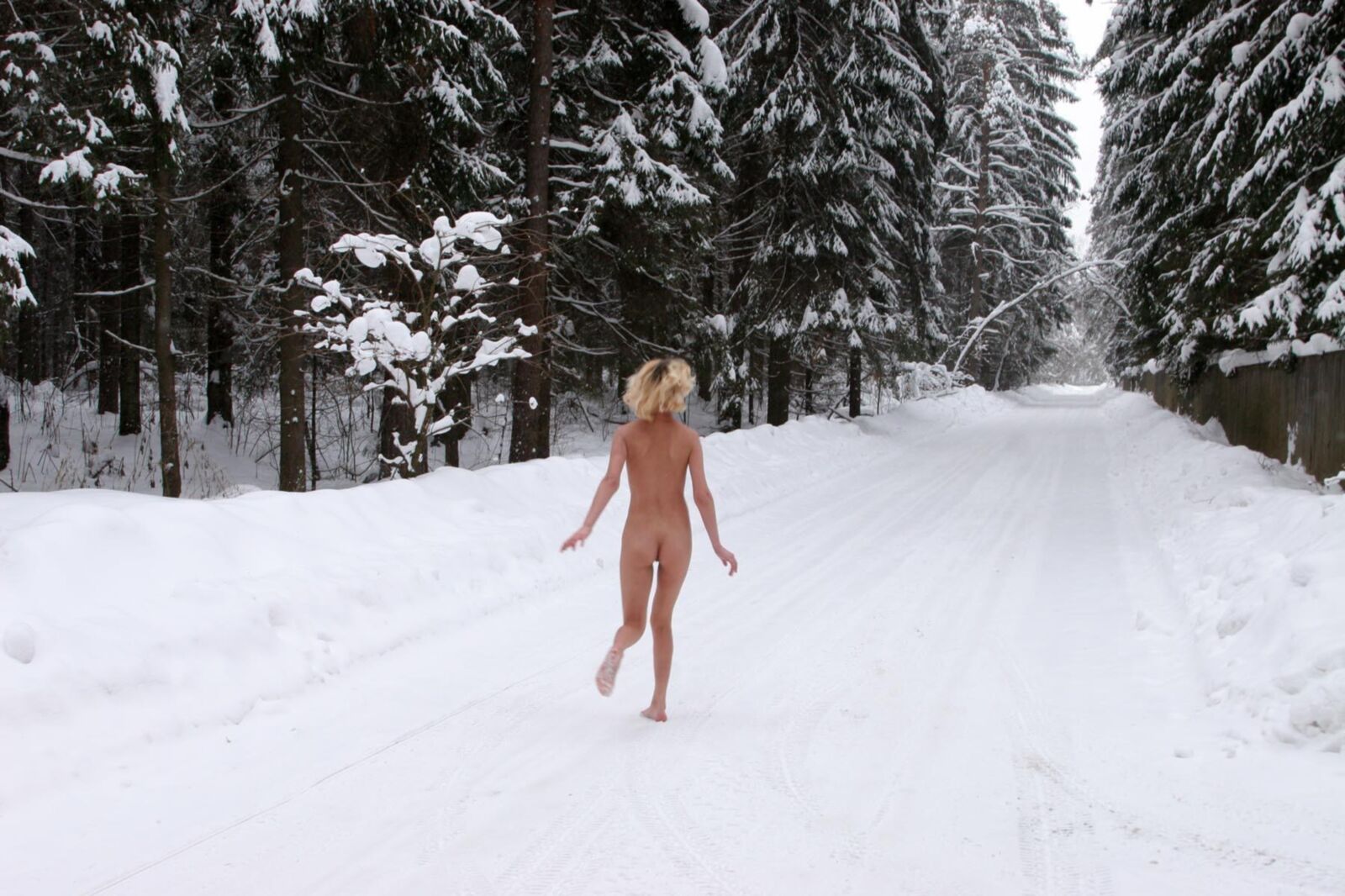 Junge Blondine pinkelt in den Schnee