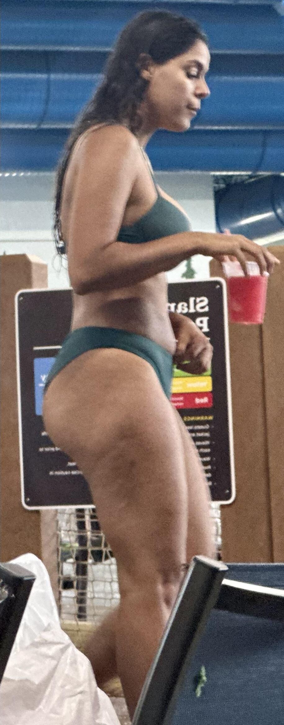 Cabello de cuervo latina en bikini verde tomando daiquiri